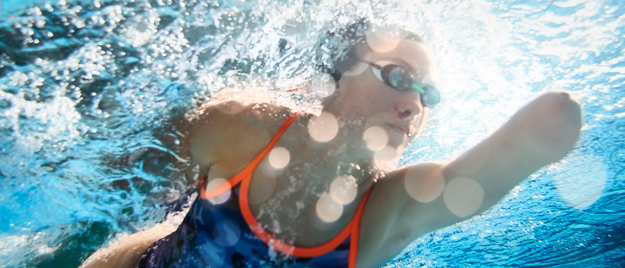 Underwater closeup of athlete with amputated arms training in a swimming pool.