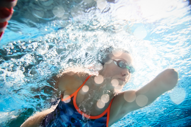Underwater closeup of athlete with amputated arms training in a swimming pool.