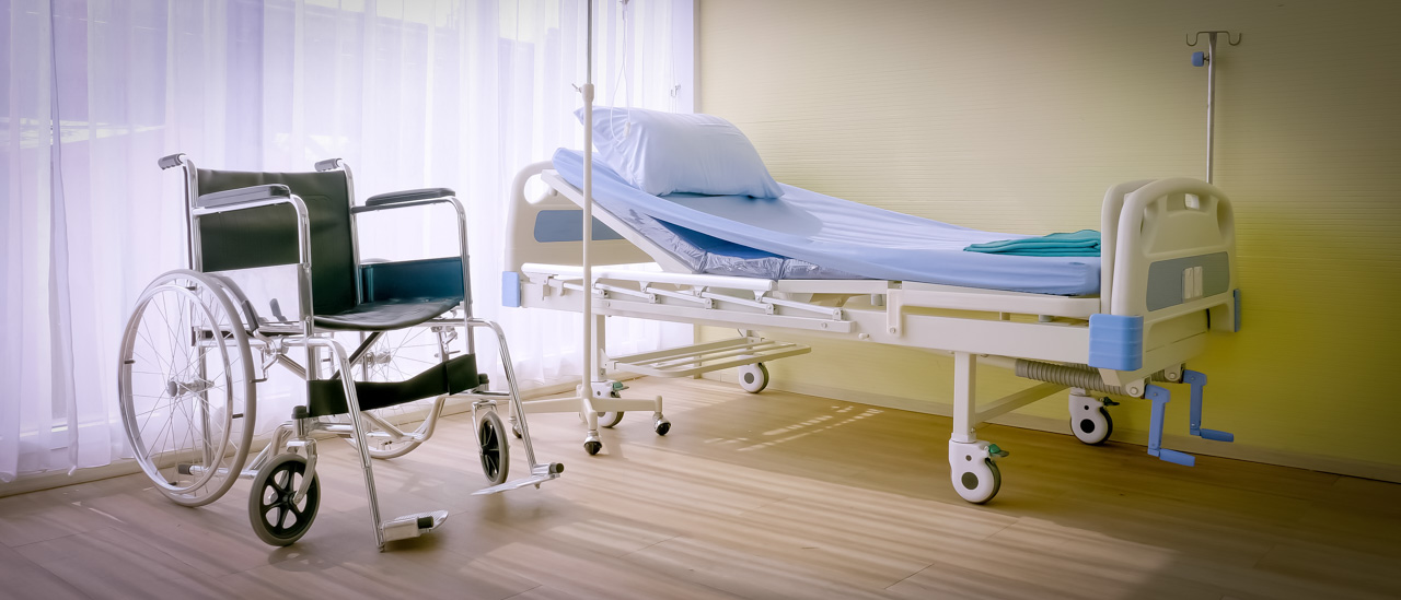 Empty hospital bed and wheelchair inside a healthcare facility.