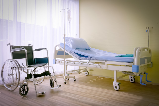 Empty hospital bed and wheelchair inside a healthcare facility.