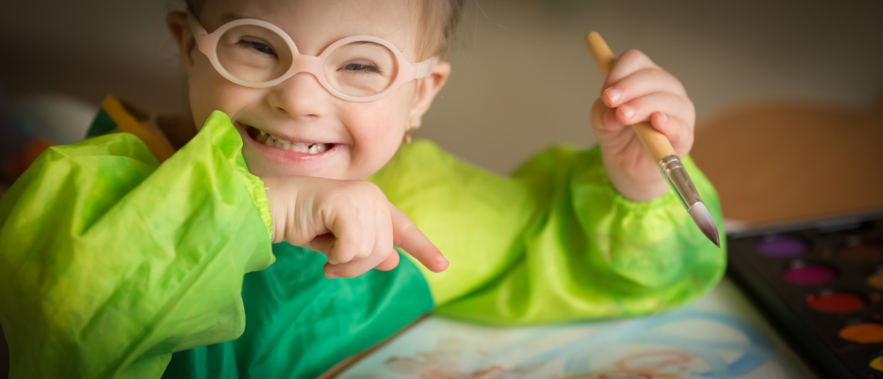 Girl with down syndrome making art and smiling.