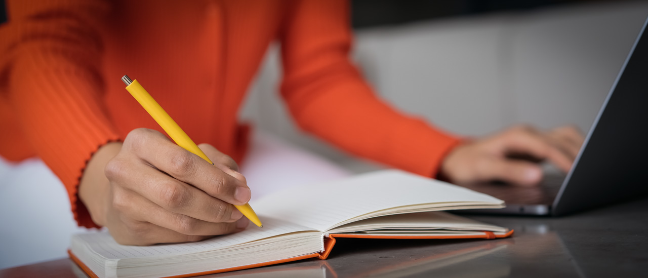 Closeup woman hand taking notes using laptop computer working online from home. 