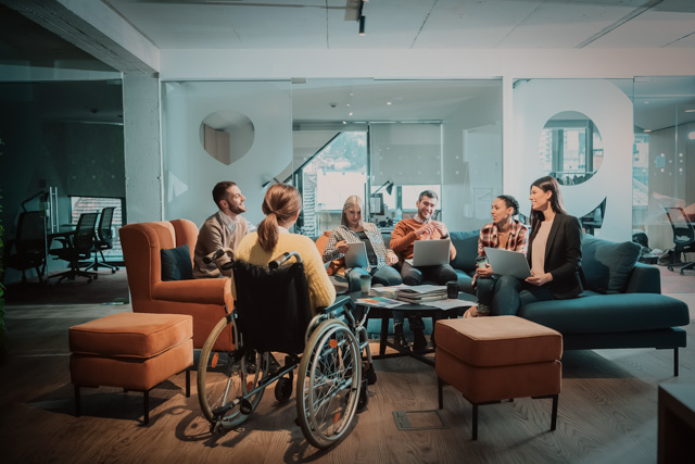 A woman in a wheelchair having a meeting with colleagues.