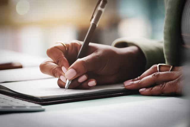 A close up of a pair of hands writing in a journal.