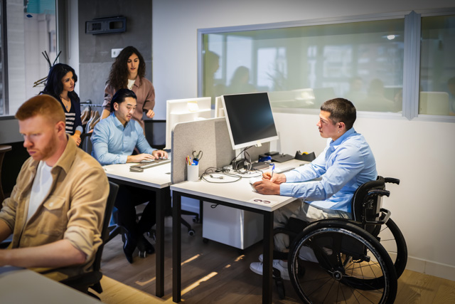 Young professionals collaborating in office, including a person with disability.